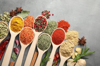 Gri masadaki kaşıklardaki farklı baharatlar düzdü.