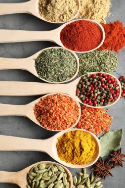 Gri masadaki kaşıklardaki farklı baharatlar düzdü.