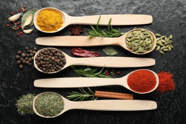 Siyah masadaki kaşıklarda bir sürü farklı baharat var.