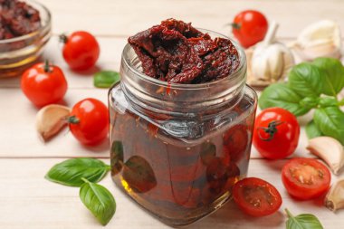 Lezzetli güneşte kurutulmuş domatesler, taze sebzeler, fesleğen ve sarımsak beyaz ahşap masada, yakın plan.