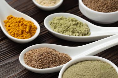 Tahta masadaki kaşıklarda farklı süper yiyecek tozları, yakın plan.