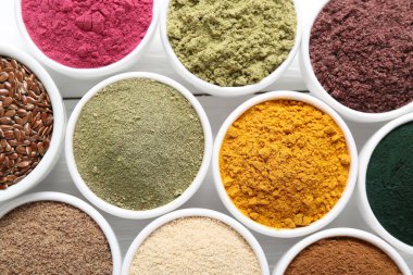 Beyaz ahşap masadaki kaselerdeki farklı süper yiyecek tozları.