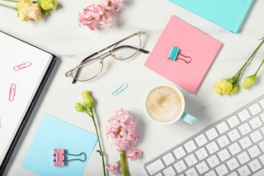 Beyaz mermer masa üzerinde kırtasiye, çiçek ve kahve ile düz kompozisyon yatıyordu