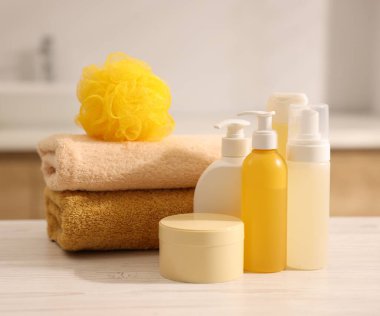 Banyodaki beyaz ahşap masada farklı banyo ürünleri.