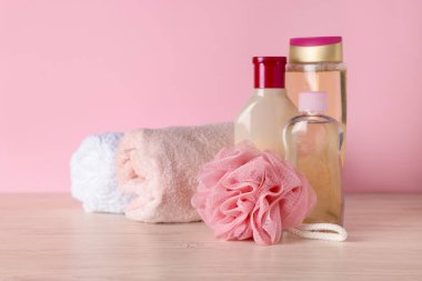 Açık ahşap masa üzerinde farklı banyo aksesuarları, pembe arka plan, yakın çekim