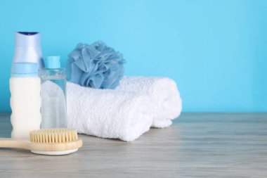 Açık mavi arka planda, ahşap masada farklı banyo aksesuarları, yakın plan. Metin için boşluk