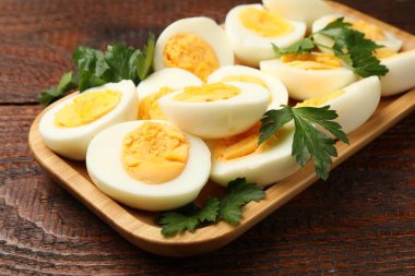 Ahşap masada haşlanmış yumurta ve maydanoz, yakın plan.