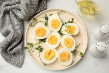 Haşlanmış yumurta, mikro yeşillik ve beyaz mermer masa üzerinde yağ, düz uzanmış