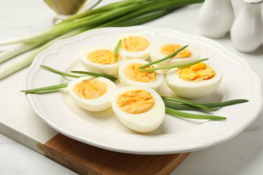Beyaz masada yeşil soğanlı haşlanmış yumurtalar, yakın plan.
