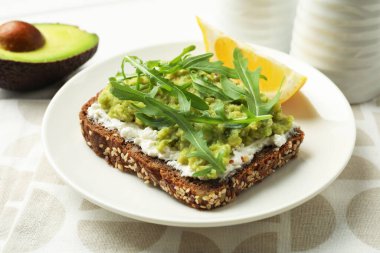 Avokado, krem peynir, roka ve limon dilimli lezzetli sandviç, yakın plan.