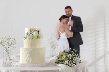 Mutlu evli çift içeride, düğün pastasına ve masadaki bukete odaklan.