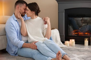 Evdeki şöminenin yanında oturan sevimli çift.