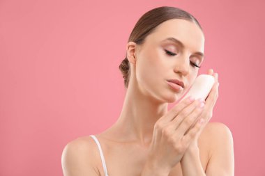 Pembe arka planda sabun çubuğu olan güzel bir kadın. Metin için boşluk