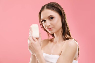 Pembe arka planda köpüklü sabun çubuğu olan kadın.