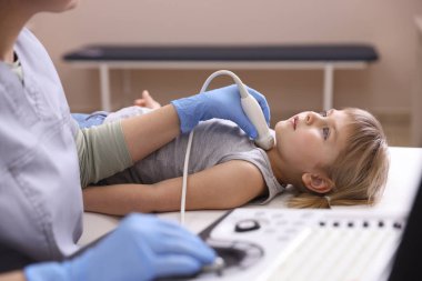 Sonograf, klinikte küçük kızın tiroid bezini ultrason muayenesi yapıyor.
