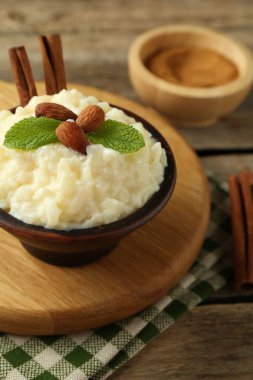 Bademli lezzetli sütlaç, nane ve tarçınlı çubuklar ahşap masada, yakın plan.