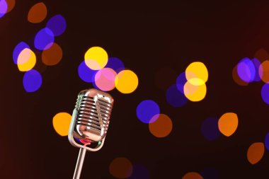 Karanlık arka planda bulanık ışıkları olan klasik mikrofon, mesaj için yer. Müzik ekipmanları