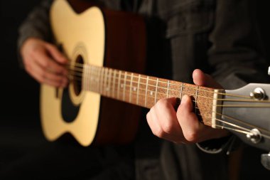 Siyah arkaplanda gitar çalan adam, yakın plan