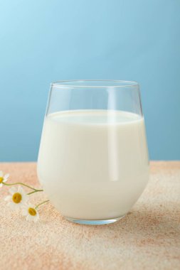 Açık mavi arkaplan üzerinde cam taze süt, yakın plan
