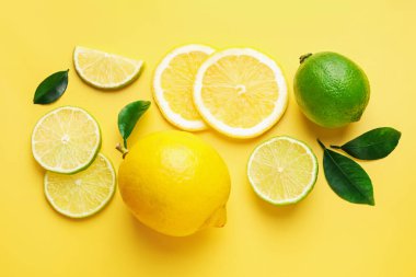 Taze limon, limon ve yeşil yapraklar sarı arka planda, düz yerde