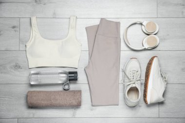 Spor kıyafetleri, spor ayakkabıları, su şişesi ve havlu yere.