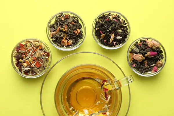 Cam fincanda nefis bitki çayı ve yeşil arka planda kuru yapraklar.