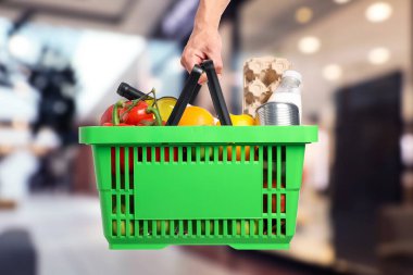 Süpermarkette elinde farklı gıda ürünleri olan bir adam var.