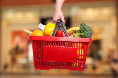 Süpermarkette elinde farklı gıda ürünleri olan bir adam var.