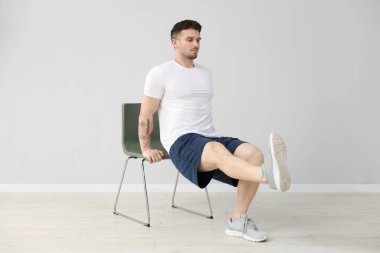 Evde sandalyeyle egzersiz yapan yakışıklı adam.