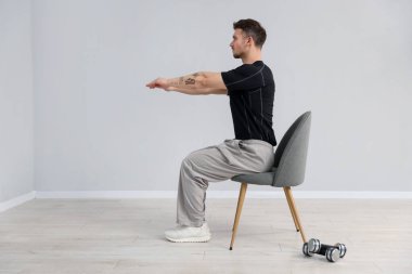 Evde sandalyeyle egzersiz yapan yakışıklı adam.