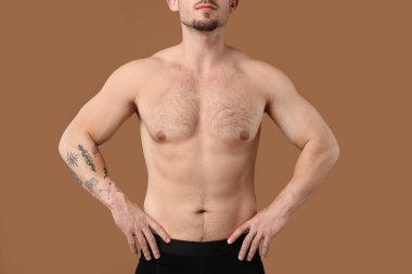 Kıllı göğüslü, kahverengi arka planda genç bir adam, yakın plan. Epilasyon işlemi