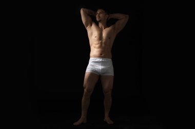 Siyah arka planda beyaz iç çamaşırlı genç bir adam.