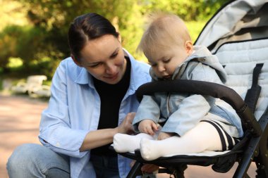 Parkta bebek arabasında sevimli bebeğiyle annesi
