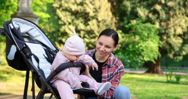 Parkta bebek arabasında sevimli bebeğiyle annesi