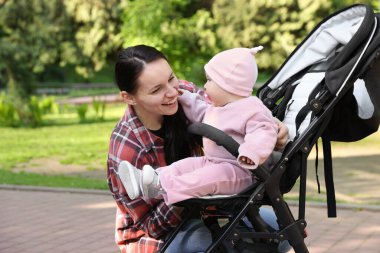 Parkta bebek arabasında sevimli bebeğiyle annesi