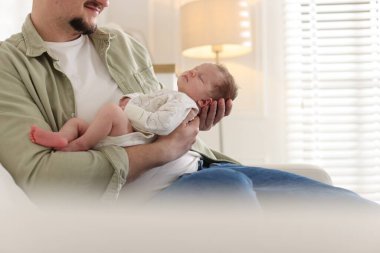 Baba, yeni doğmuş bebeğini kanepeye yatırmış, yakın plan. Metin için boşluk