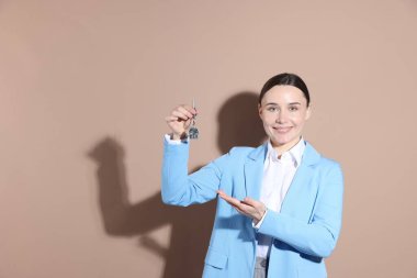 Emlakçının elinde bej arka planda anahtarlık metin için boşluk var.