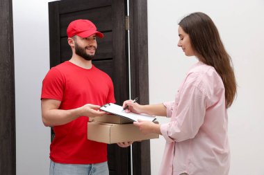 Kutularla gülümseyen kurye ve paket teslimatı için imza atan alıcı.