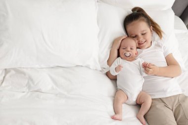 Sevimli kız ve küçük kız kardeşi evde yatakta, mesaj atmak için yer var.