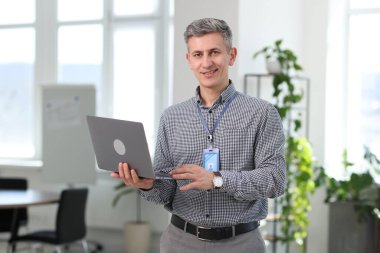 Ofiste dizüstü bilgisayarla gülümseyen mühendisin portresi