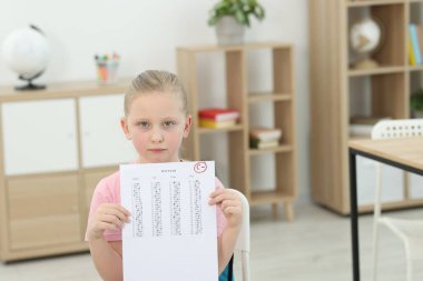 Okul derecesi. Kapalı alanda C harfi ve eksi sembolle cevap kağıdını tutan üzgün kız.