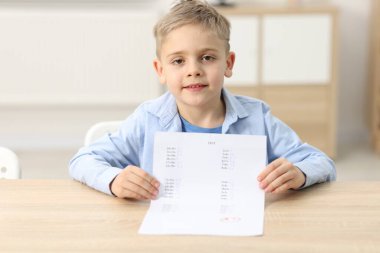 Okul derecesi. A harfiyle cevap kağıdını tutan mutlu çocuk ve kapalı bir masada sembol.