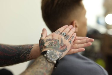 Berber dükkanında müşteriyle çalışan profesyonel berber, yakın plan.