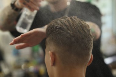 Berber dükkanında müşteriyle çalışan profesyonel berber, yakın plan.