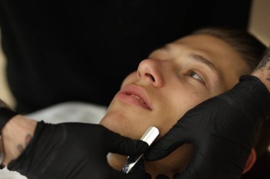 Berber dükkanında müşteriyle çalışan profesyonel berber, yakın plan.