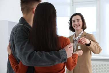 Emlakçı, evin yeni sahiplerine evin anahtarını veriyor.