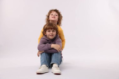 Beyaz arka planda poz veren şirin küçük kardeşler.