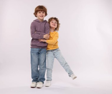 Beyaz arka planda kucaklaşan sevimli küçük kardeşler.