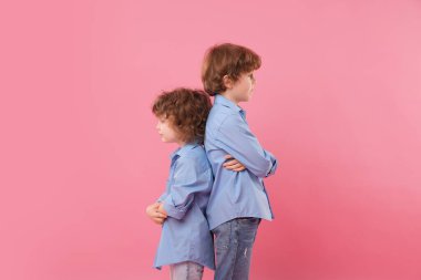 Şirin küçük kardeşler arka arkaya pembe arka planda