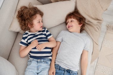 Sevimli küçük kardeşler birlikte kanepede yatıyorlar, manzaranın üstünde.